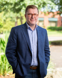 A headshot of Tom Engel in an outdoor setting.